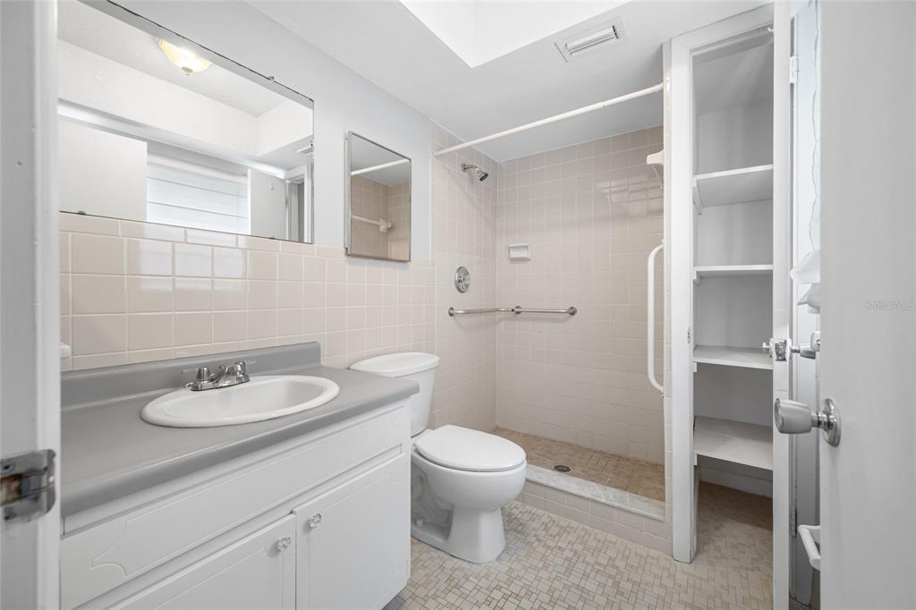 50 Liberty Way, Unit 10 Palm Harbor, FL 34684 - Photo 14 of 23 a bathroom with a granite countertop sink toilet a mirror and shower