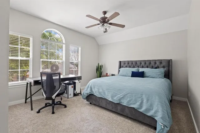 a bedroom with a bed a table and chair with a large window