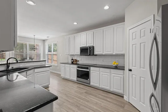 a kitchen with white cabinets appliances and sink