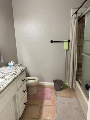 a bathroom with a granite countertop sink a toilet and a shower
