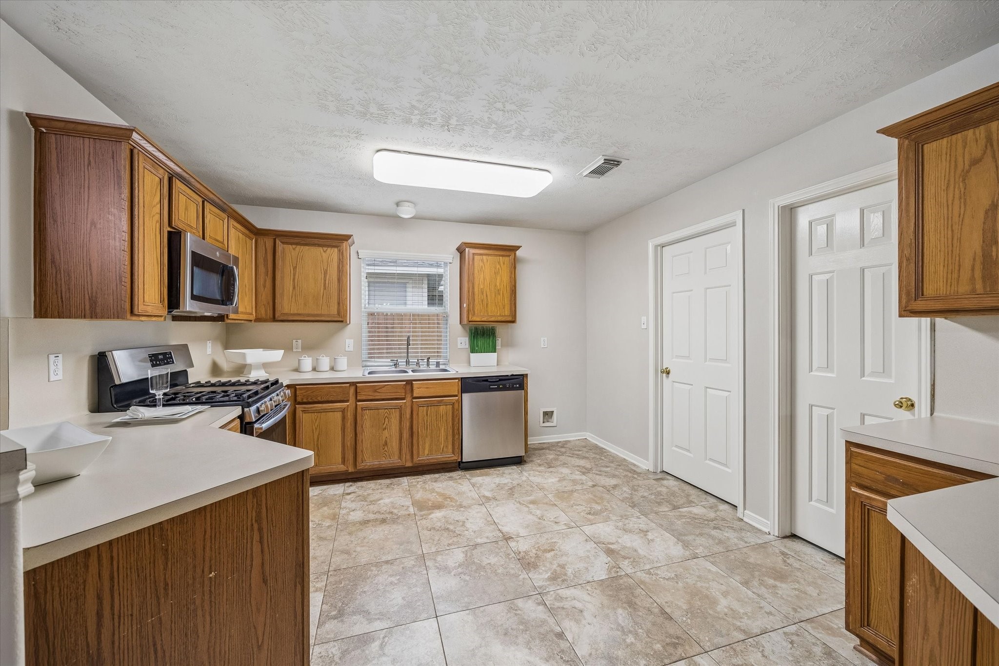 10307 Turrett Point Lane Houston, TX 77064 - Photo 3 of 12 a kitchen with a stove a sink a microwave a counter top space and cabinets