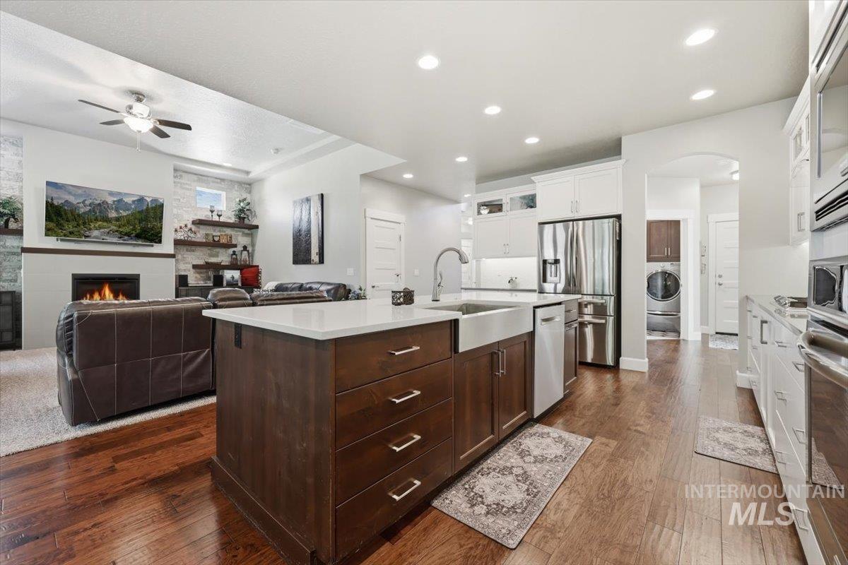 1303 West Brando Street Meridian, ID 83646 - Photo 12 of 49 Kitchen island with an undermount farmhouse sink, a gooseneck faucet, and quartz countertops