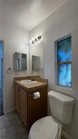 a bathroom with a granite countertop toilet sink and mirror