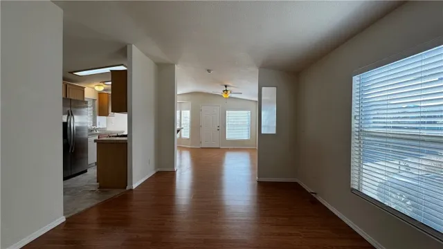 a view of a hallway with wooden floor and a kitchen