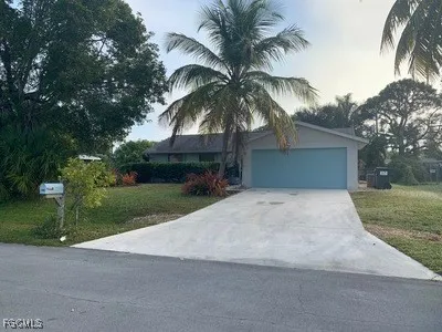 front view of house with a yard and palm trees