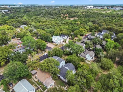 an aerial view of residential houses with outdoor space and trees