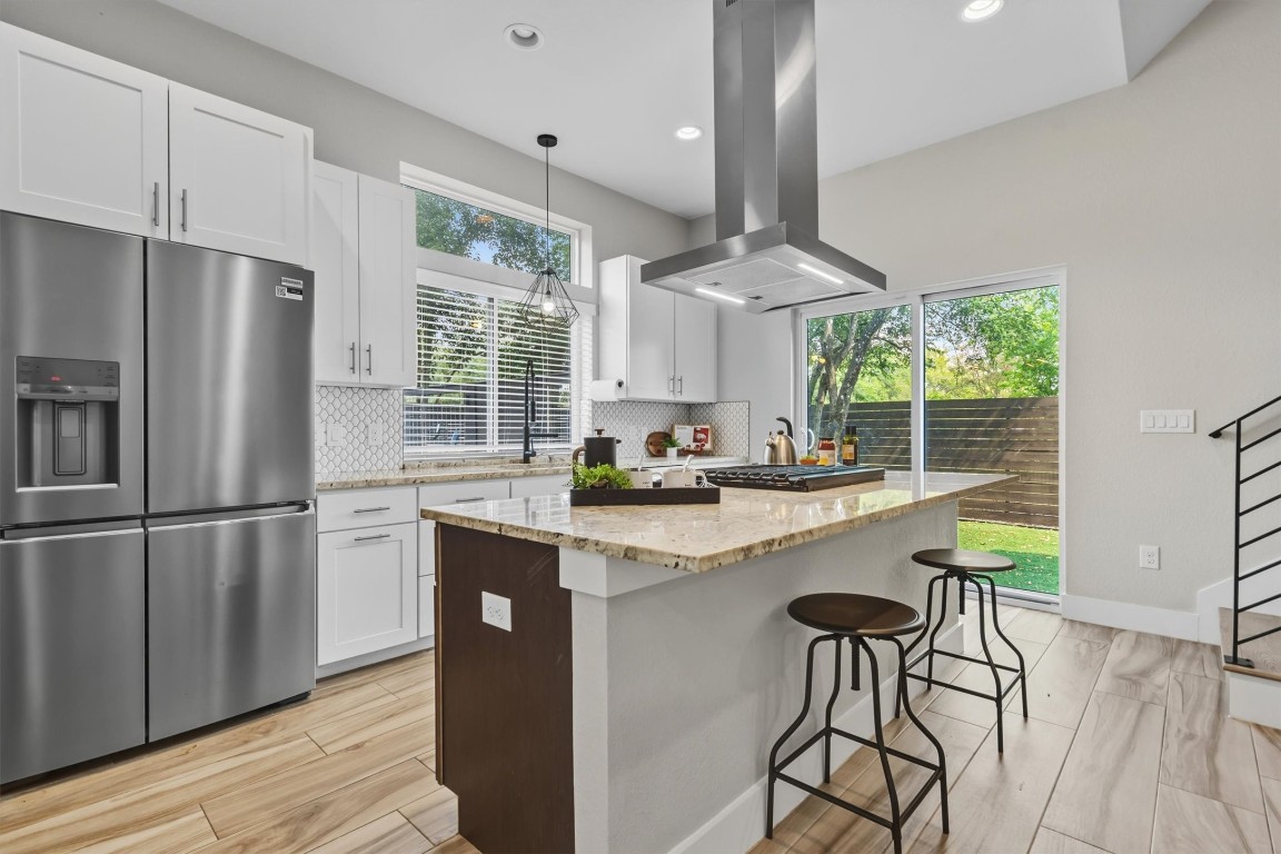 5609 Tura Lane, Unit A Austin, TX 78721 - Photo 8 of 39 a kitchen with stainless steel appliances granite countertop a refrigerator a sink dishwasher a stove and white cabinets with wooden floor