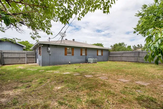 a backyard of a house with wooden fence and large trees