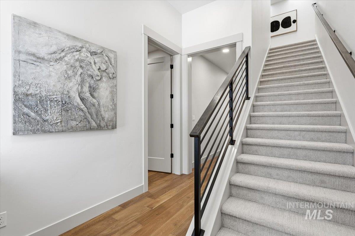 6762 South Messner Way Meridian, ID 83642 - Photo 3 of 35 Staircase featuring light gray carpeting, dark wood handrails, and black metal balusters