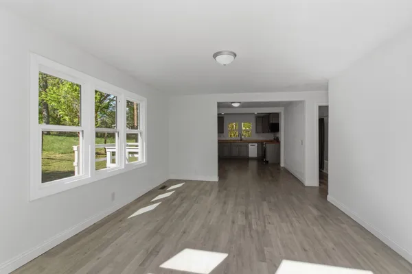 a view of an empty room with a window and wooden floor
