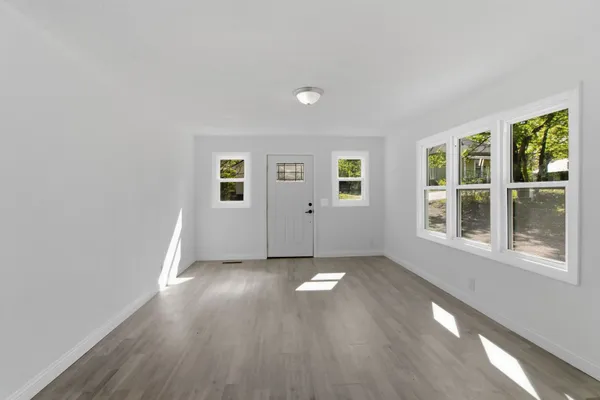 an empty room with wooden floor and windows