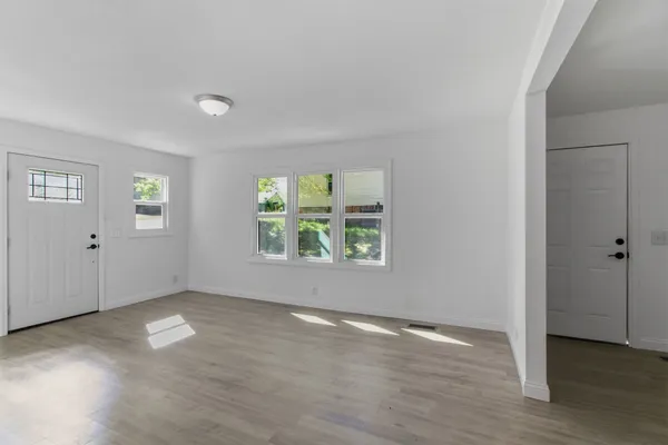 an empty room with wooden floor and windows