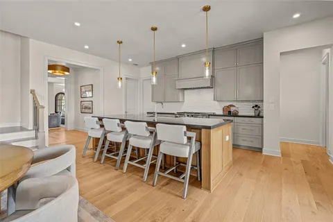 a kitchen with stainless steel appliances granite countertop a stove top oven a sink a dining table and chairs with wooden floor