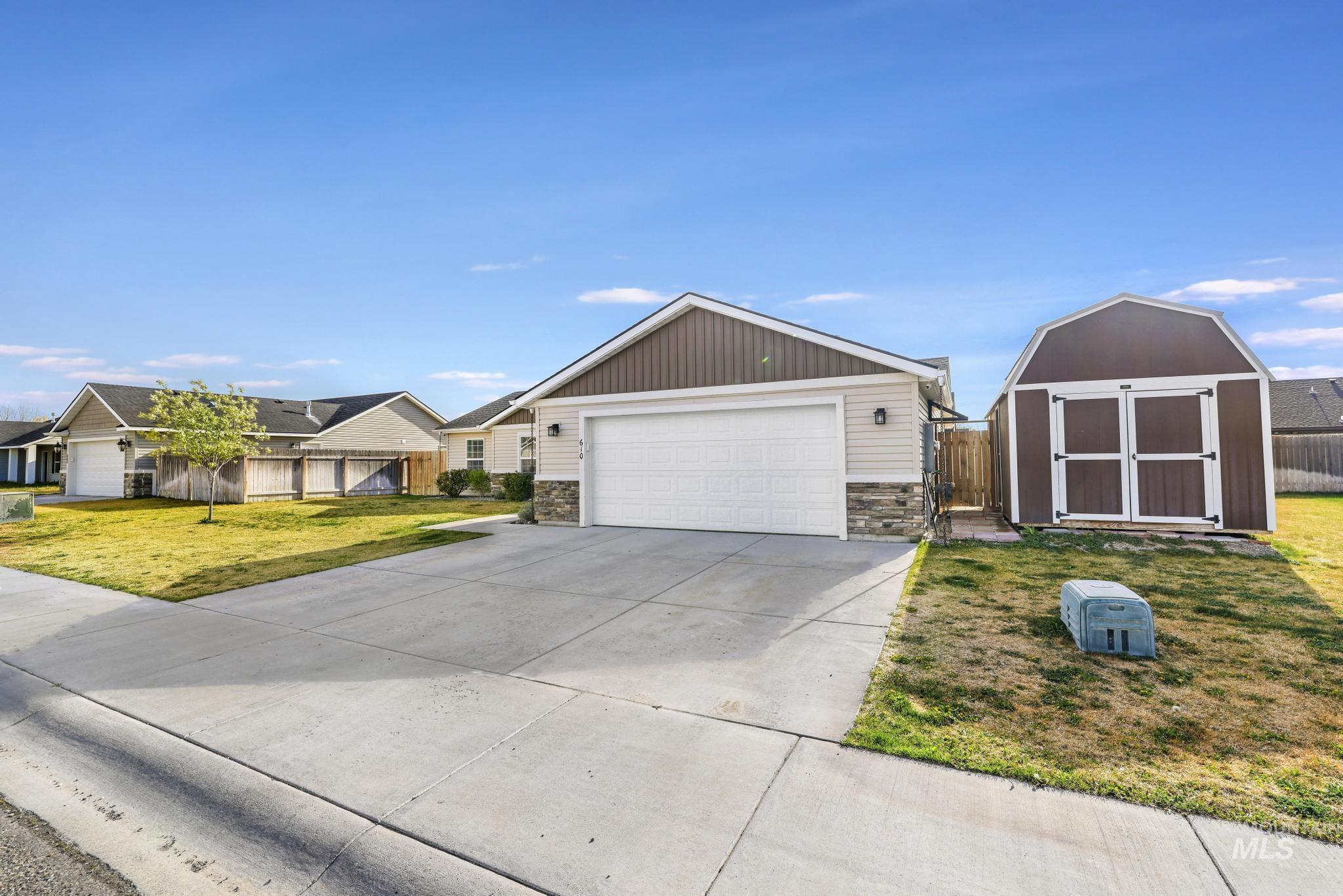 View of front of home featuring a shed, driveway, stone siding, and an attached garage