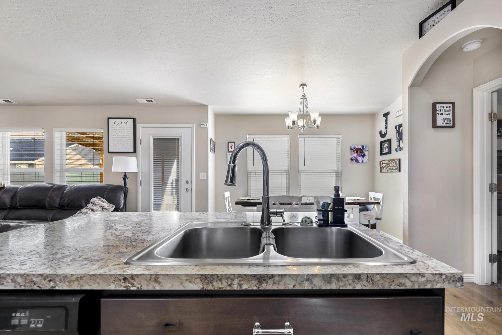 610 South B Street Rupert, ID 83350 - Photo 26 of 26 Kitchen with open floor plan, light countertops, a chandelier, dark wood finish cabinets, and a textured ceiling