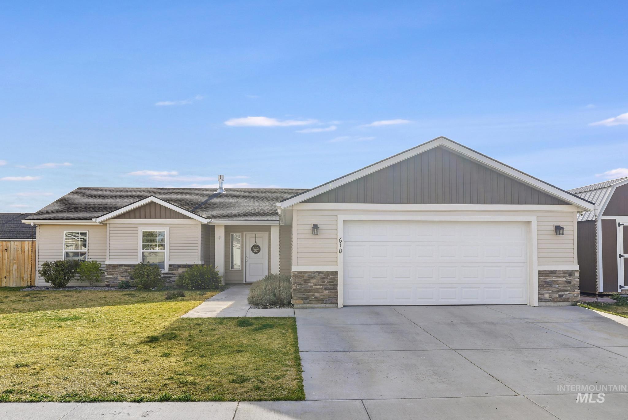 610 South B Street Rupert, ID 83350 - Photo 2 of 26 View of front of house with stone siding, concrete driveway, a front lawn, an attached garage, and a shingled roof