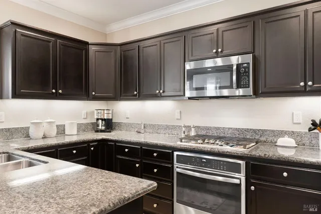 a large living room with stainless steel appliances granite countertop couches a flat screen tv with kitchen view