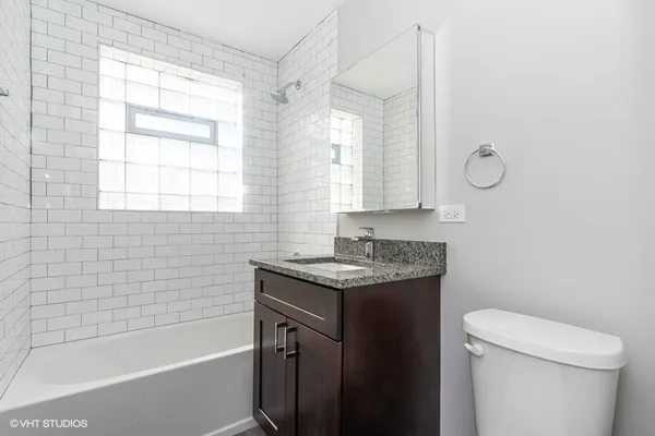 a bathroom with a granite countertop sink a toilet and shower