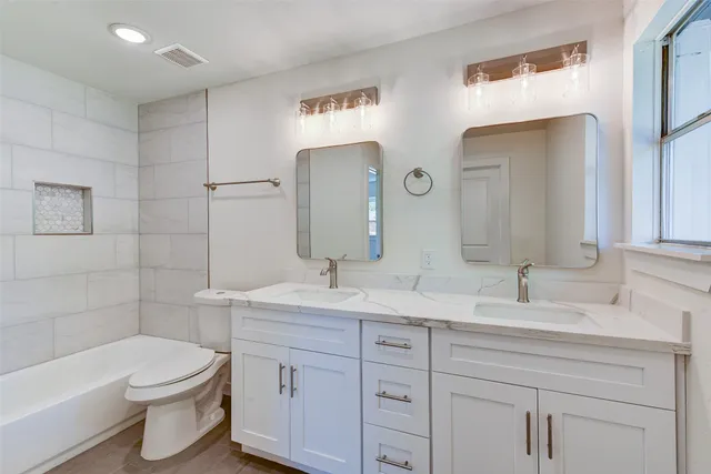 a bathroom with a toilet a sink a tub and mirror