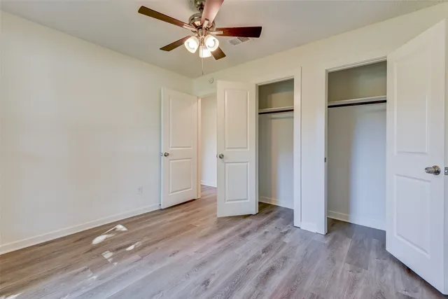 an empty room with wooden floor and a ceiling fan