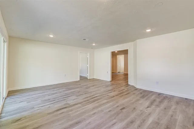 a view of an empty room with wooden floor and closet