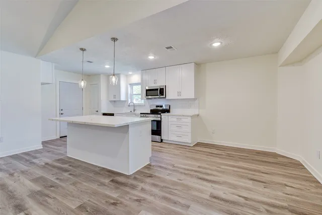 a large kitchen with kitchen island a sink a center island stainless steel appliances and a cabinets