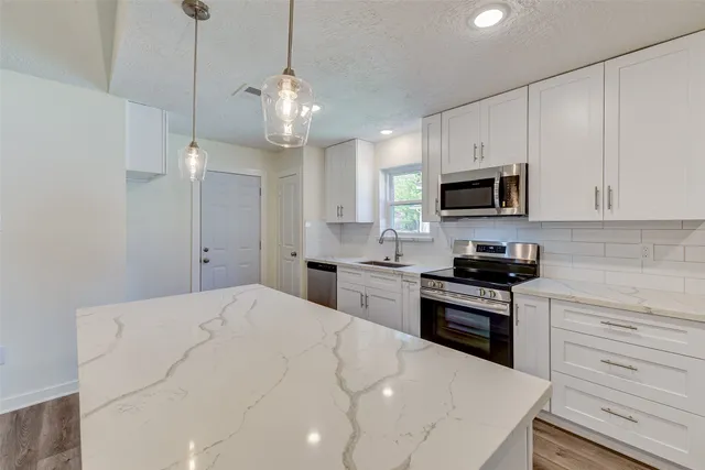 a kitchen with kitchen island granite countertop a stove top oven a sink a counter space and cabinets