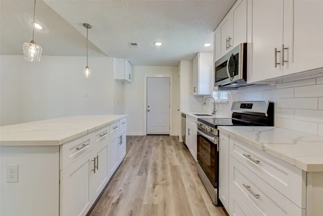 a kitchen with white cabinets stainless steel appliances and sink