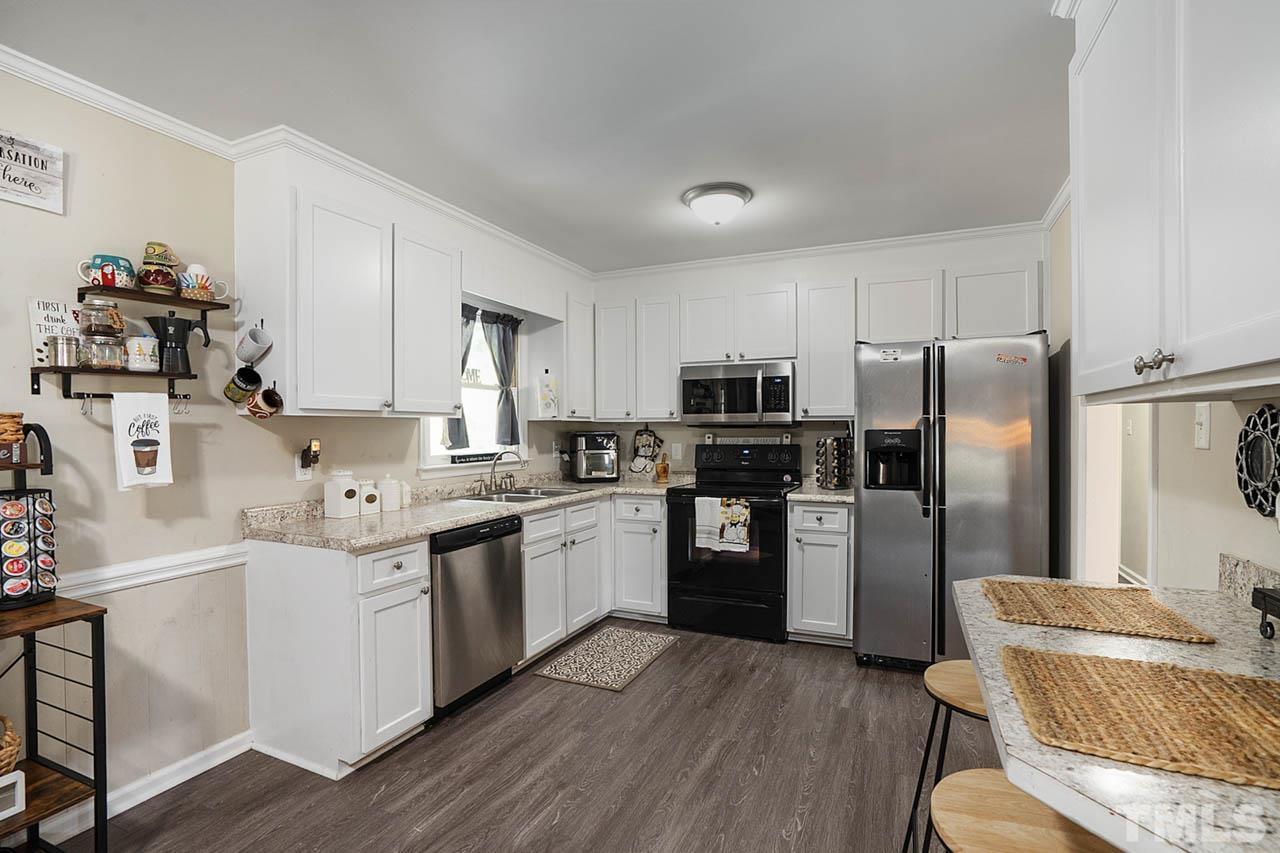 479 Ridgecrest Trail Henderson, NC 27537 - Photo 4 of 19 a kitchen with stainless steel appliances kitchen island granite countertop a refrigerator a sink dishwasher a dining table and chairs with wooden floor