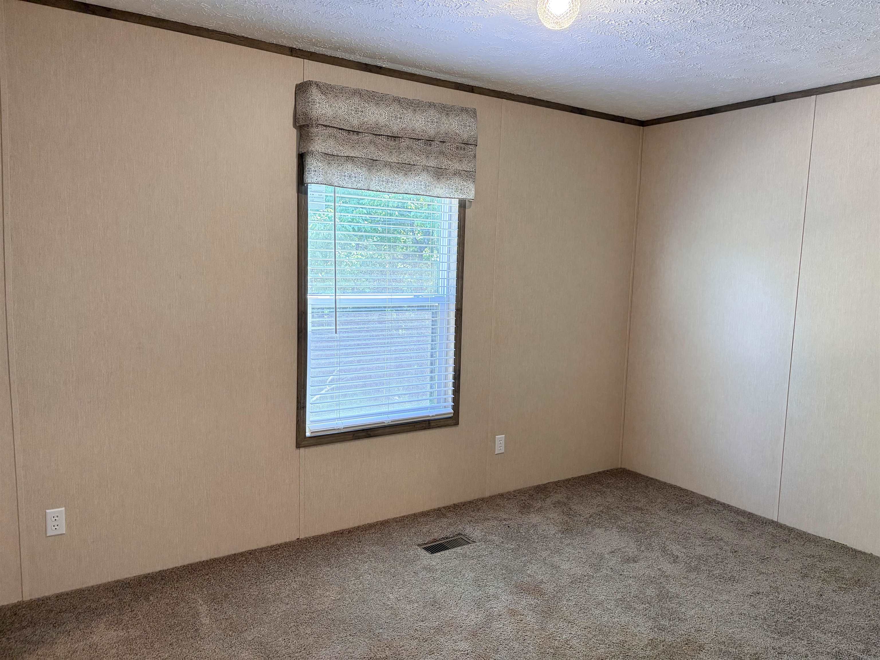 2030 Nubbin Ridge Road Middleton, TN 38052 - Photo 21 of 28 Interior room with textured beige wall panels, brown carpet flooring, and a window with blinds and a fabric valance