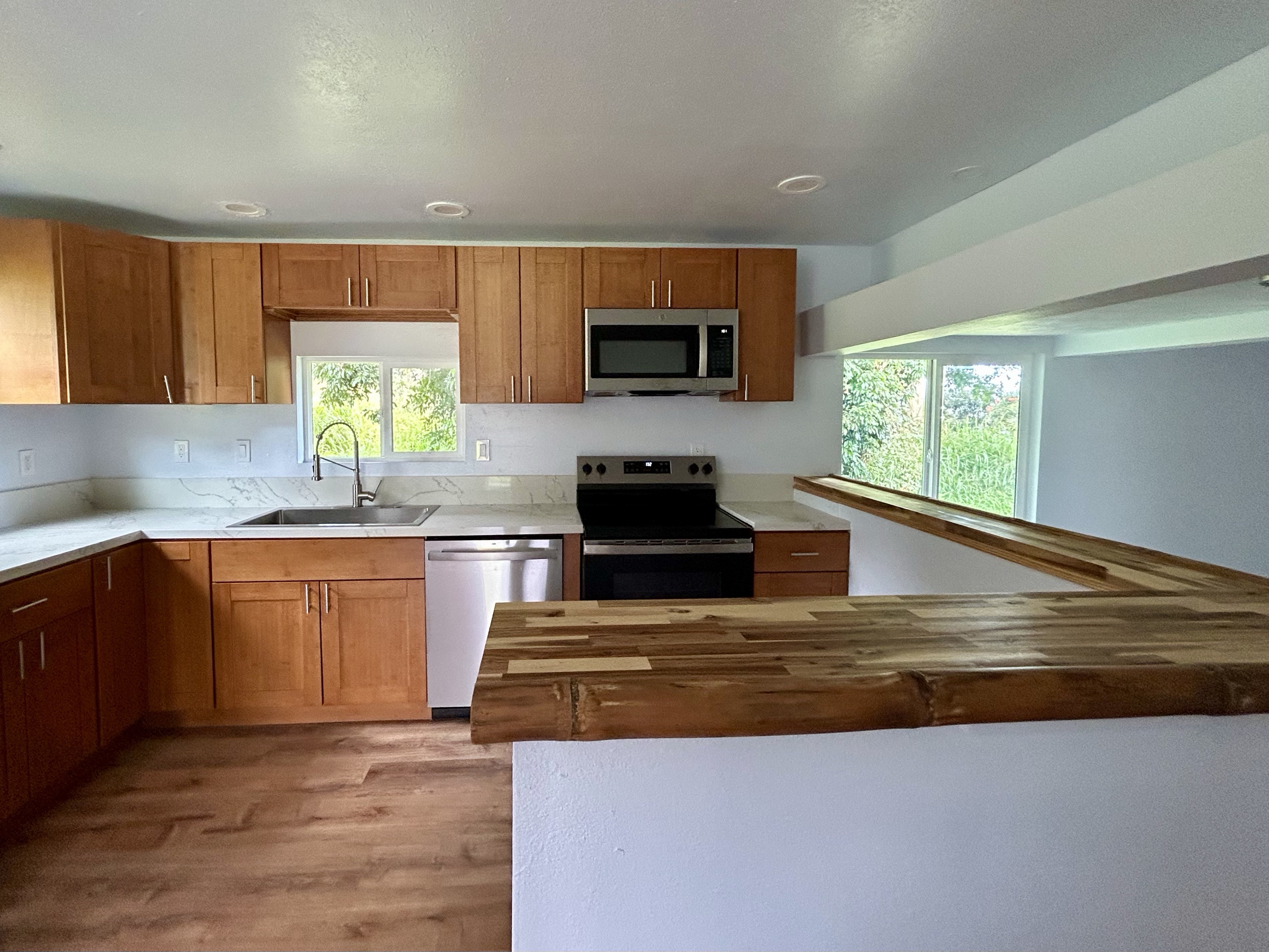82-6136 D Road, Unit B Captain Cook, HI 96704 - Photo 12 of 30 a kitchen with stainless steel appliances granite countertop a stove a sink and a microwave