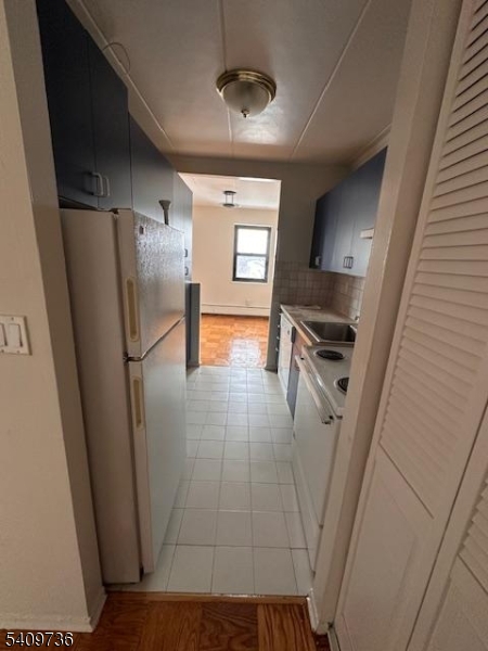 77 Prospect Avenue, Unit H Hackensack, NJ 07601 - Photo 6 of 17 a view of a refrigerator in kitchen and an empty room