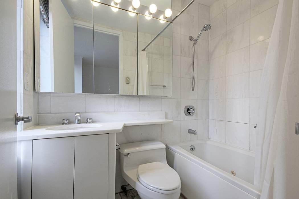 161 West 61st Street, Unit 15E Manhattan, NY 10023 - Photo 10 of 24 a bathroom with a sink a toilet and shower