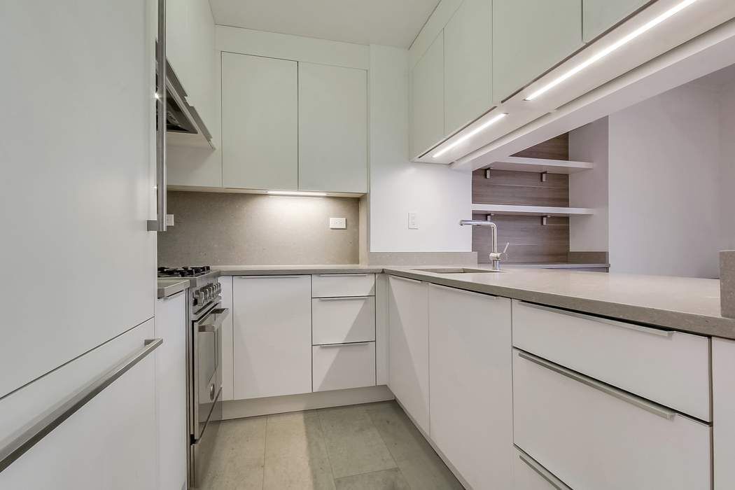 161 West 61st Street, Unit 15E Manhattan, NY 10023 - Photo 8 of 24 a kitchen with granite countertop a sink a stove and cabinets