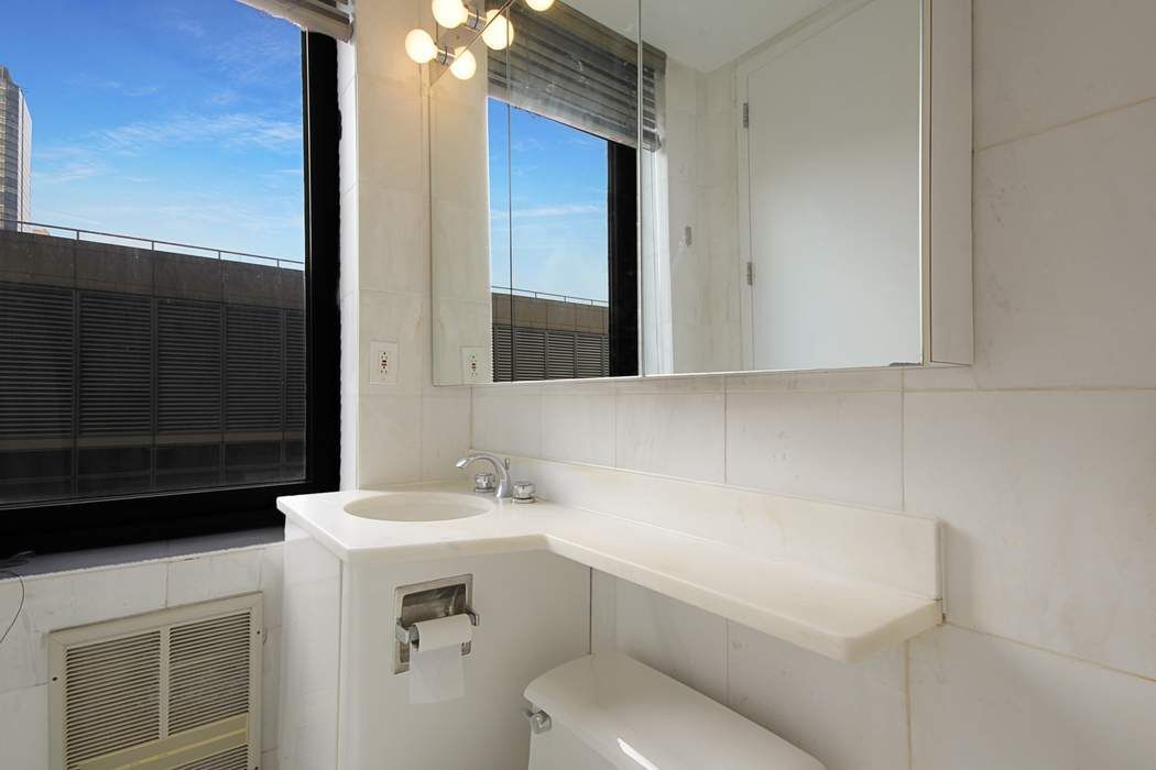 161 West 61st Street, Unit 15E Manhattan, NY 10023 - Photo 9 of 24 a bathroom with a toilet sink and mirror