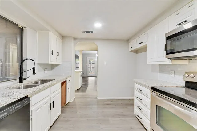 a kitchen with stainless steel appliances granite countertop a sink and a stove top oven with wooden floor