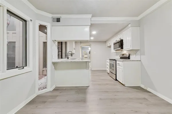 a view of a kitchen with wooden floor and electronic appliances