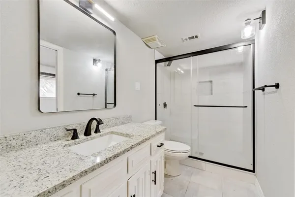 a bathroom with a granite countertop sink toilet and shower