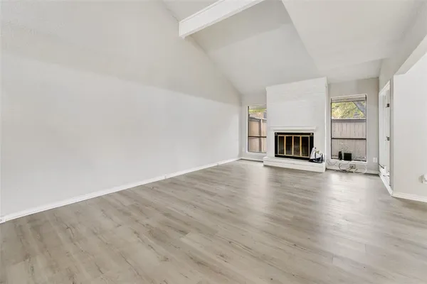 a view of empty room with fireplace and wooden floor