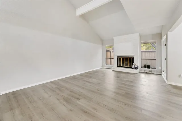 a view of empty room with fireplace and wooden floor