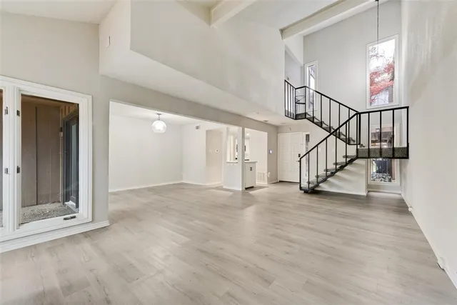 a view of an empty room with wooden floor and stairs
