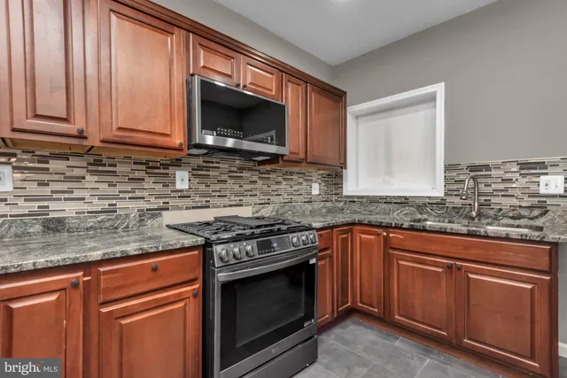 a kitchen with stainless steel appliances granite countertop a stove microwave and sink