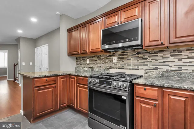 a kitchen with stainless steel appliances granite countertop wooden cabinets stove top oven and microwave