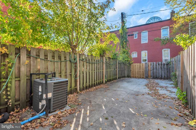 a view of a brick house with a small yard and wooden fence