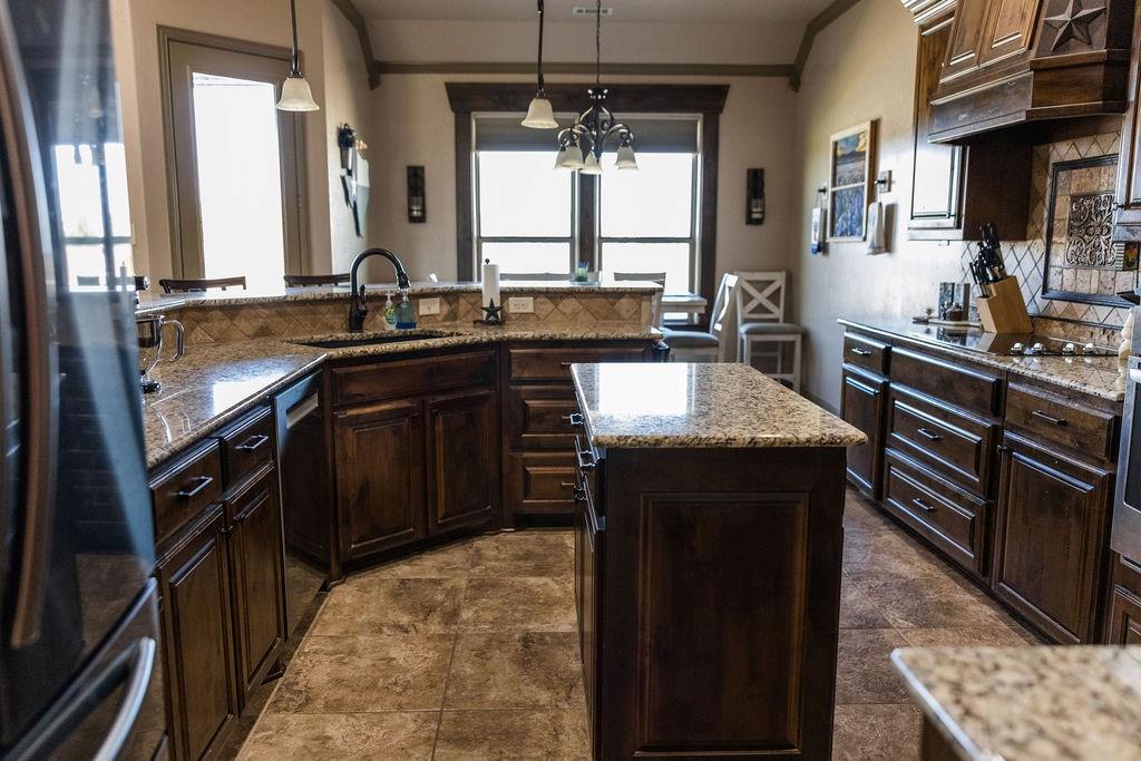 123 Cactus Drive Decatur, TX 76234 - Photo 12 of 30 Kitchen with an island, dark wood cabinetry, granite countertops, and tile flooring