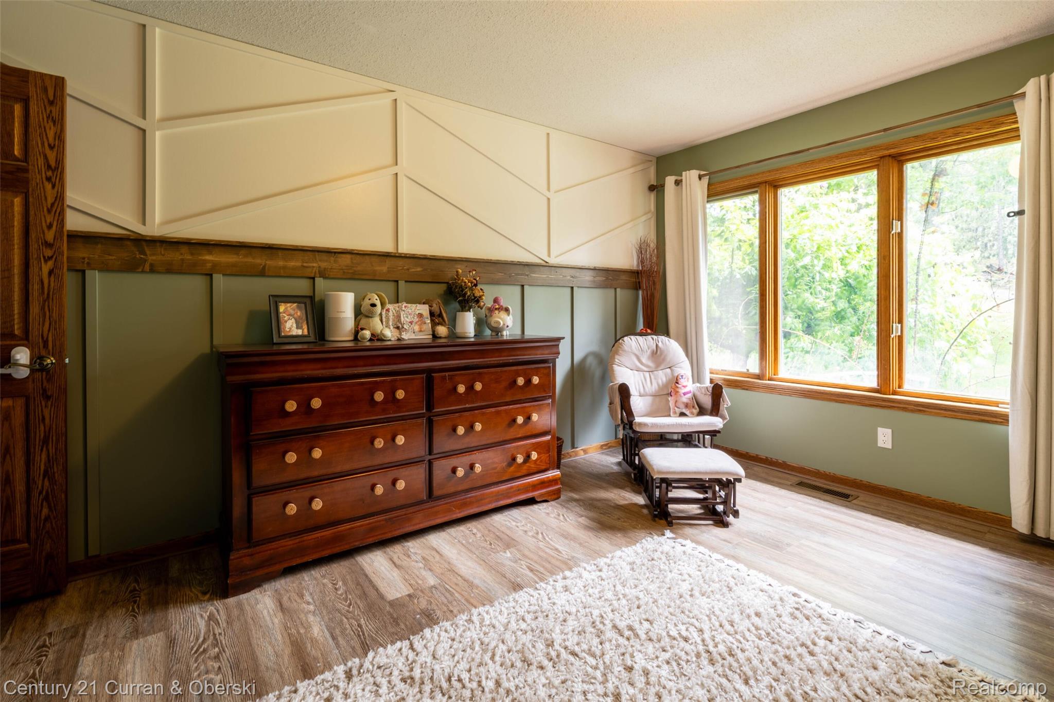 8775 Winding Rdg Drive Millersburg, MI 49759 - Photo 27 of 53 Expansive window bank with natural wood trim, wood-finish flooring, and a decorative accent wall featuring geometric paneling and wainscoting