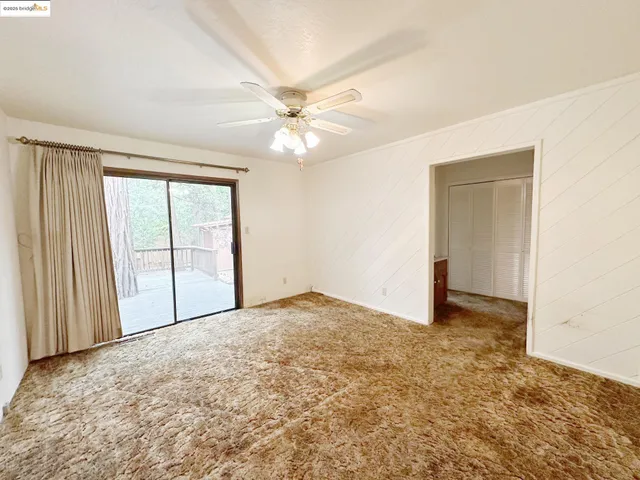 an empty room with a ceiling fan and a window