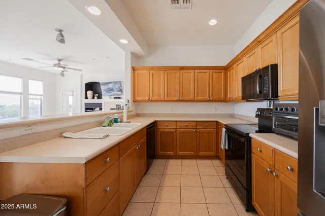 a kitchen with stainless steel appliances a sink dishwasher stove top oven and wooden cabinets