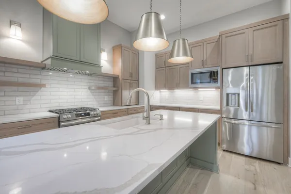 a kitchen with stainless steel appliances a sink a stove a refrigerator and cabinets