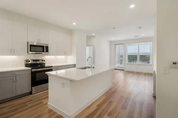 a large white kitchen with wooden floors and stainless steel appliances